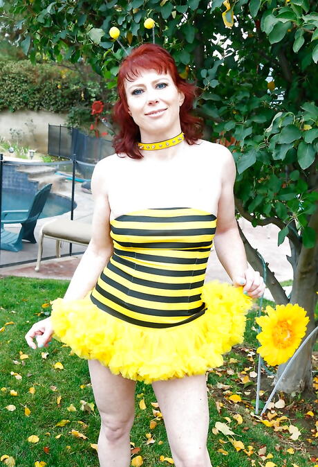 Hot american red-haired milf Amber Rayne in cosplay outfit revealing her butt and spreading her legs outdoor