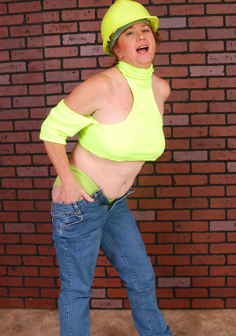 Sexig äldre säkert i enhetlig outfit visar stora bröst och sprider benen
