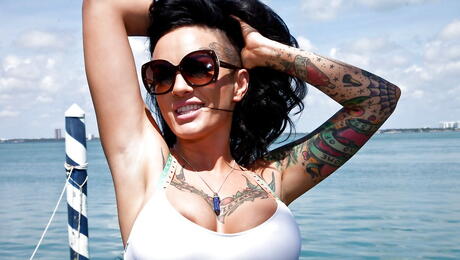 La encantadora estadounidense Lola Luscious en bikini mostrando grandes tocones y culo en la playa
