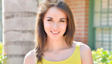 スカートをはいたアメリカ人ブルネットの若いエミリー・グレイがお尻を丸出しにして外で脚を広げる。
