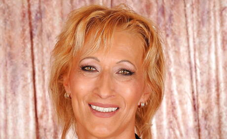 Blonde sensuelle Granny Yda en jupe fantaisie présentant de petits seins et écartant ses jambes
