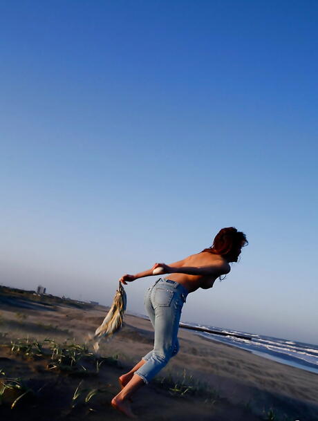 热辣日本少女里目优穿着牛仔裤在海滩上展示大奶子和性感臀部
