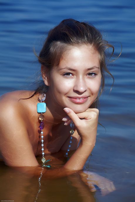 Cute teen Afrodita removes her bikini to pose nude on a sandy beach