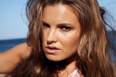 Tall teen Carina poses totally naked on a sandy beach in the water