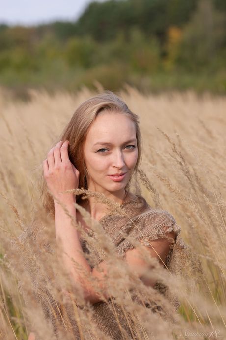 Blonde teen Jessie U highlights her perky tits while naked in tall grasses