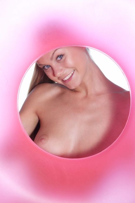 Blonde teen Nancy A removes a rubber ring to pose nude on a beach