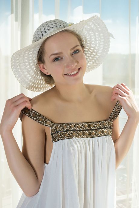 Endearing teen Faina Bona removes a sun hat and a dress to pose nude on a balcony