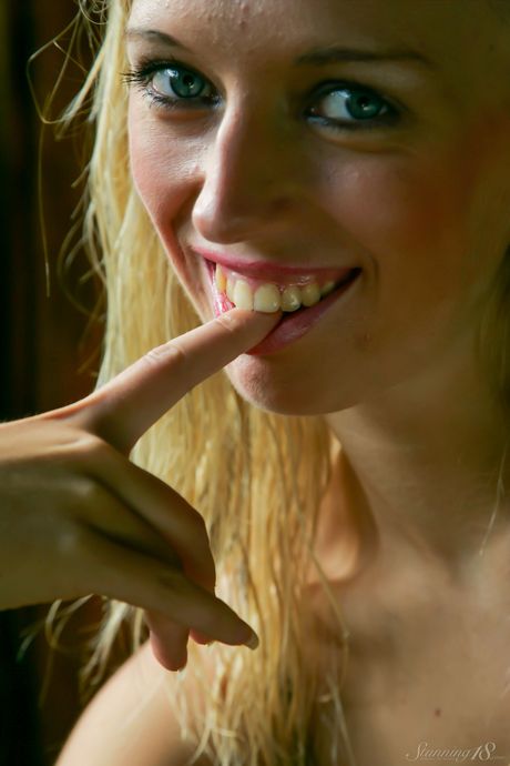 18-year-old blonde Ursa C takes off everything on a bed during a solo shoot