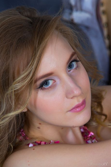 Young blonde Angela highlights her landing strip pussy while naked on a bed