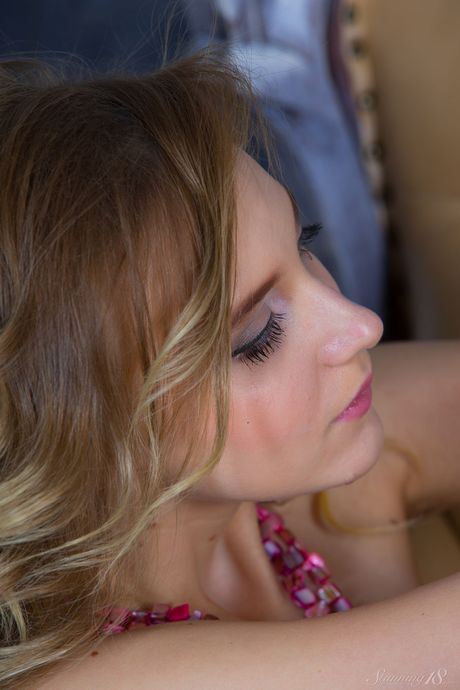 Young blonde Angela highlights her landing strip pussy while naked on a bed