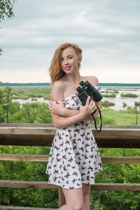 젊은 빨간 머리 헬레네가 샌들을 신고 파티오에서 알몸이 된 모습
