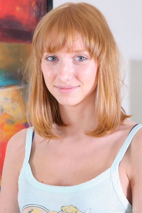 Young redhead Rhea F takes it all off on a leather sofa