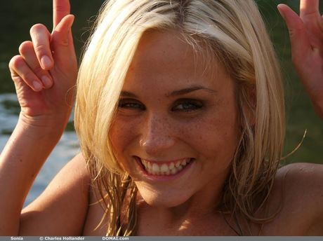 Blonde teen Sonia models totally naked on a sandy beach by herself