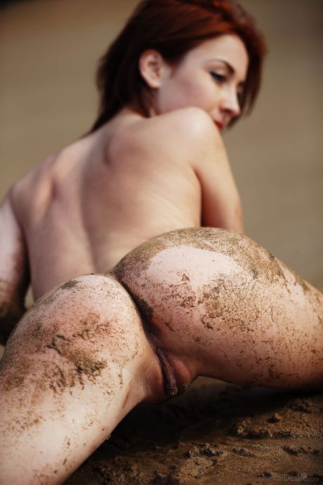 Naked redhead Night A wades into a mudflat while showing her wet pussy