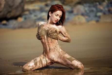 Naked redhead Night A wades into a mudflat while showing her wet pussy