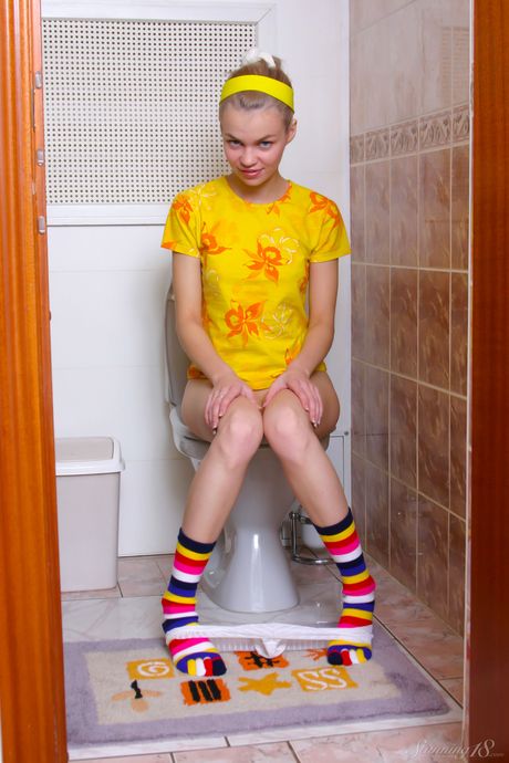 Unga blondin Cindy B bläcker sin kropp innan hon fingrar i fitta i ett badrum
