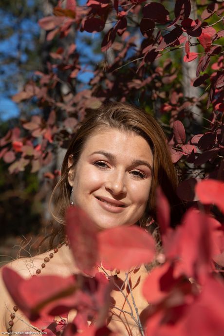 Russisch erotisch model Aphrodesia wordt naakt in een tuin terwijl bladeren veranderen
