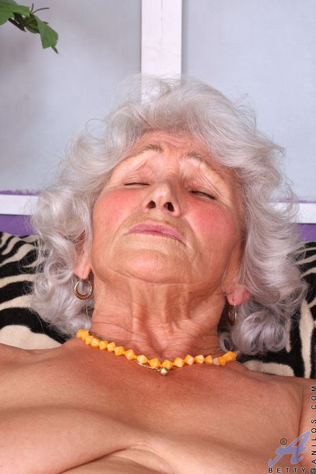 Chubby granny Betty undresses and fingers her hairy pussy in stockings