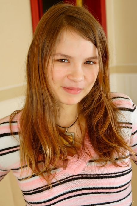 Young redhead Aurora C removes a bra and panty set to pose nude