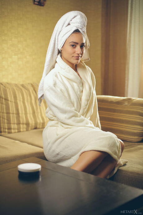 Tender teen Cira Nerri fingers her pussy after removing a bathrobe on a sofa