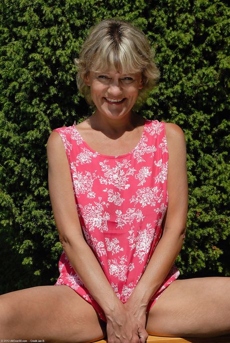 Mature woman Sherry D shows her pussy and tits while sitting on a bench