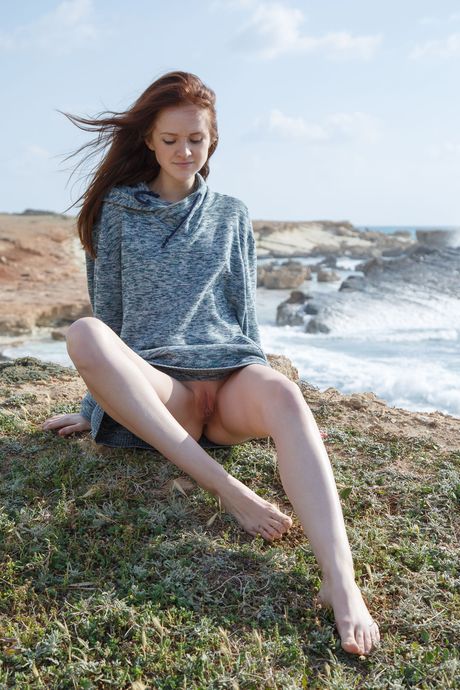 A adolescente magra Alice May fica nua em uma praia rochosa
