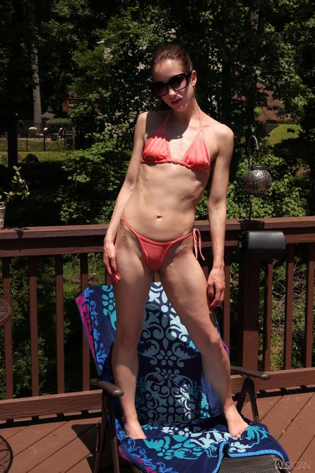 Naked teen Nadia Noja removes her bikini to pose nude in a backyard