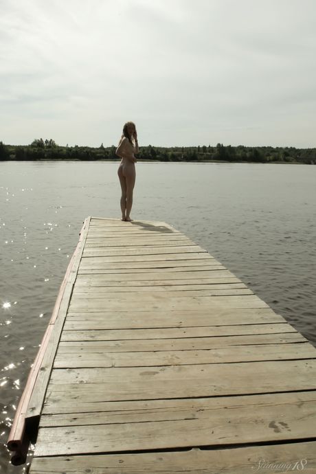 Young blonde Jenny D bares it all on a dock in the middle of a lake