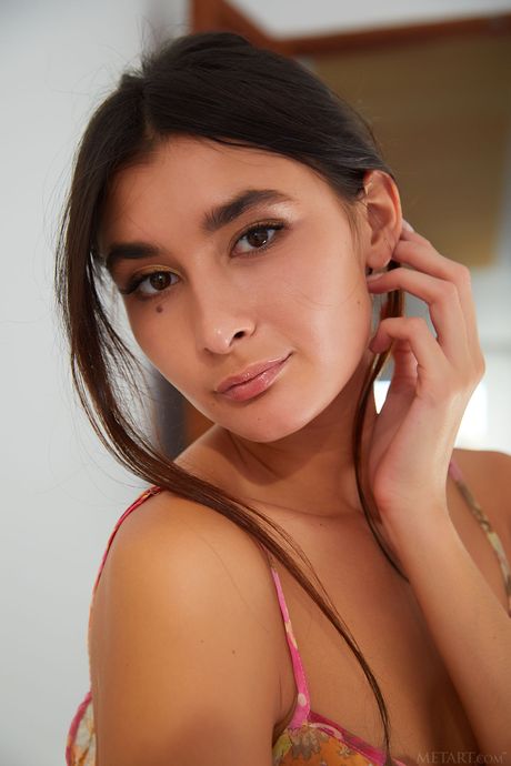 Charming teen Bambi Joli removes her dress and panties to pose nude on a stool