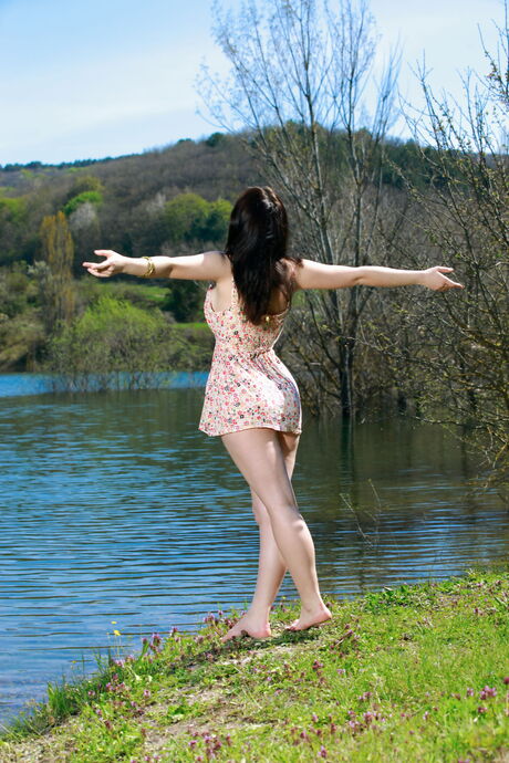 Amazing babe Sivilla takes off her dress to pose nude on a dock in the forest