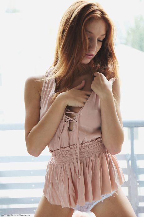 Young redhead Micca removes a bra and panty set to get naked on her bed