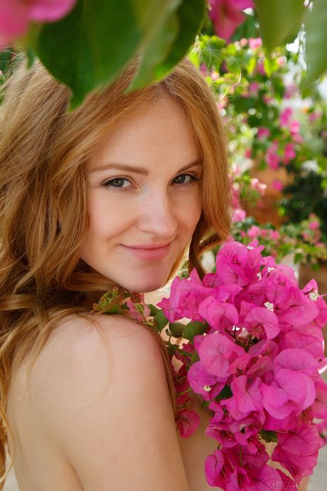 Young redhead Alice May bares her body on a balcony in the garden