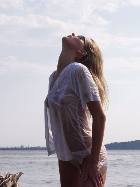 Blonde teen Models No Name gets naked in a shallow pool of water