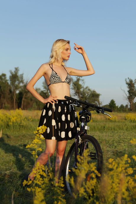 Sexy blonde Kira W strips naked in a field and poses with a bike