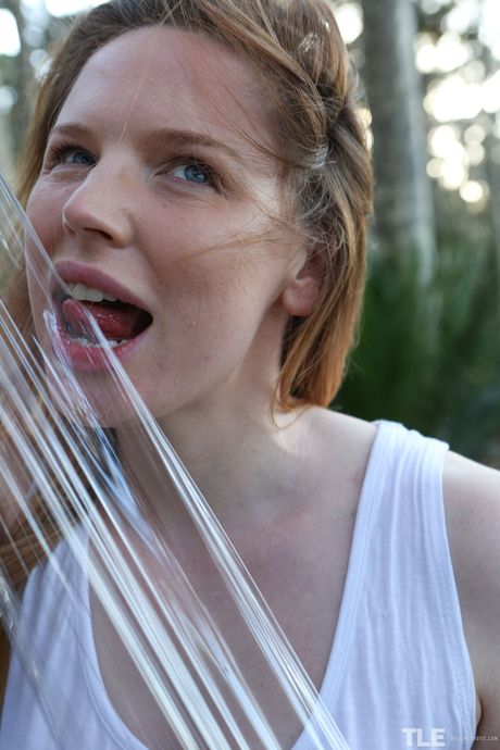 Pale redhead Madison Missina wraps herself in plastic wrap while naked in the bush