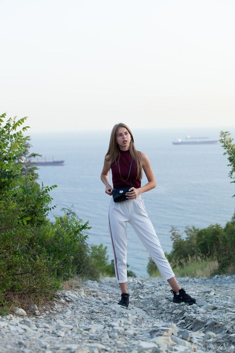 Blonde teen Rina bares her body on a dock in the water