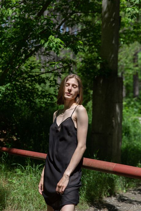 Blond tenåring Anna R går naken på en innkjørsel foran en bar
