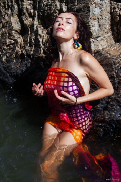 Young brunette Madivya gets naked in shallow water during solo action