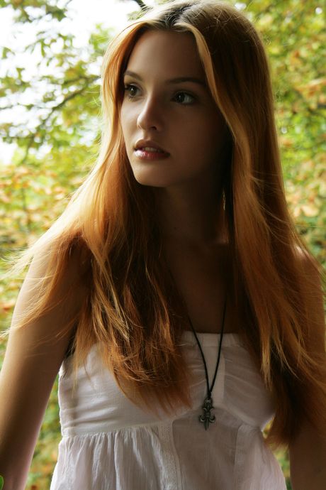 Sexy redhead Kira W strips to her high heels and poses naked in a solo