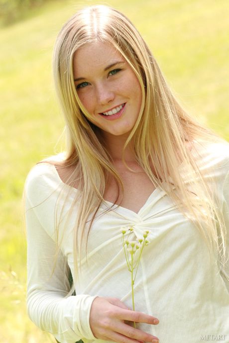 Ligh-haired teen Jewel A bares her body on a blanket in a field of flowers