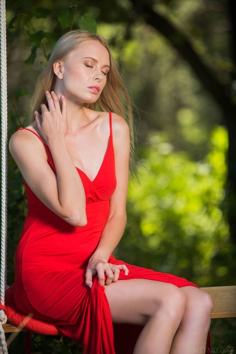 Blonde teen Maria Rubio removes a red dress to pose nude on a swing