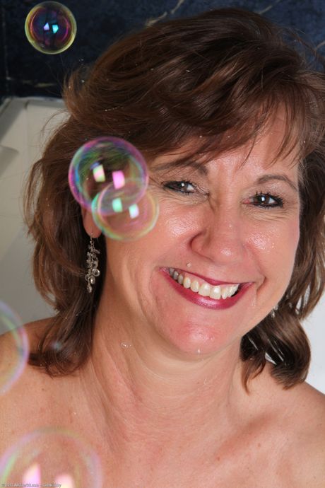 Mature woman Lynn toys her pussy with multiple dildos in a bubble bath