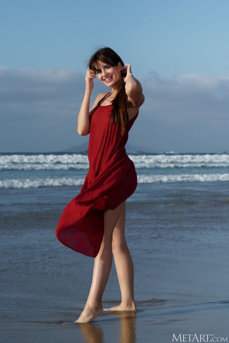 Bashful teen Leni Doll gets completely naked on a sandy beach