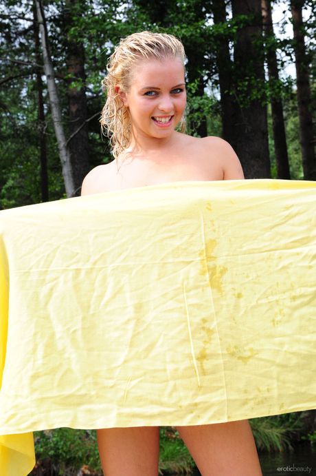 Blonde teen Berry A models totally naked on a dock in the middle of a lake
