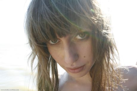 Young brunette Lilly B gets naked on a beach without shyness