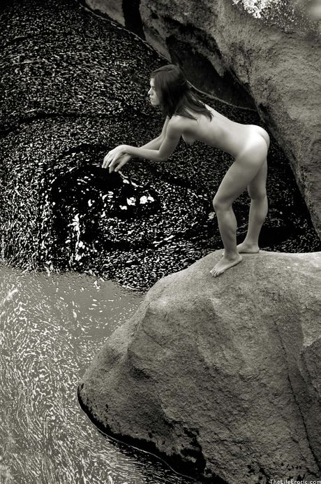 Lean teen Anette bares it all on rocks by a river and shows her tiny tits