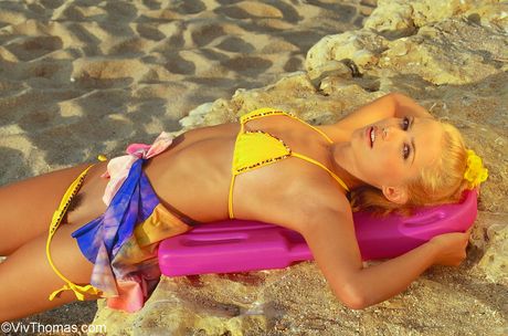 Bionda adolescente e una spoglia su una spiaggia sabbiosa
