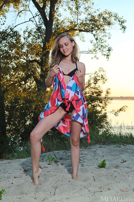 Svelte teen Lucretia K gets naked on a beach at sunset by herself