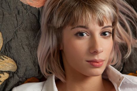 Blonde teen Queva bares it all on a bed in a confident fashion