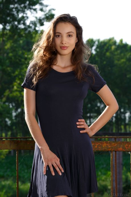 Brunette teen Calypso Muse removes a dress to pose nude on a patio